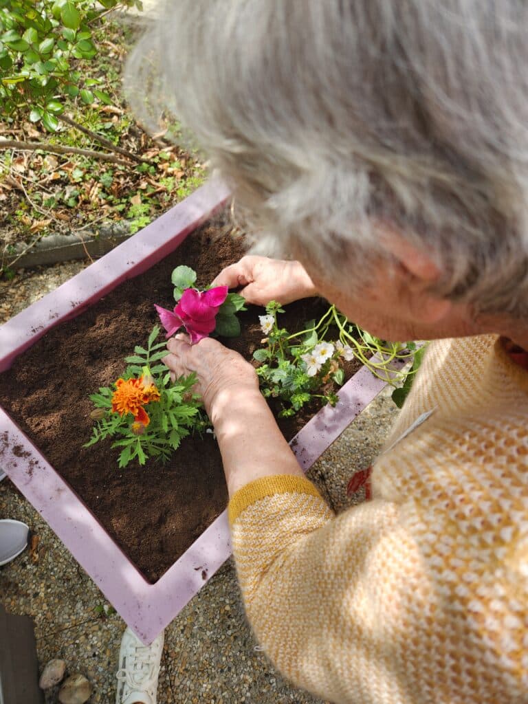 Femme âgée en train de planter une fleur